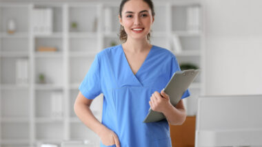Female medical assistant with clipboard in clinic.