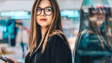 Stock Photo ID: 1216896508 Attractive fashion blogger standing near show-window in a mall with mobile phone in hands and writing a rewiew about the shop she visited. Shopping, black friday sale, blogging, freelancing concept.