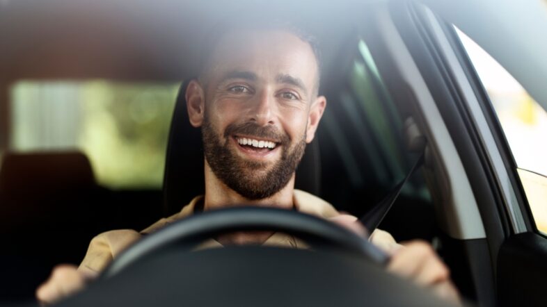 Handsome smiling latin man driving a car. Car sharing concept.