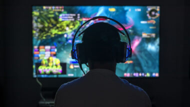 Young gamer playing video game wearing headphone.