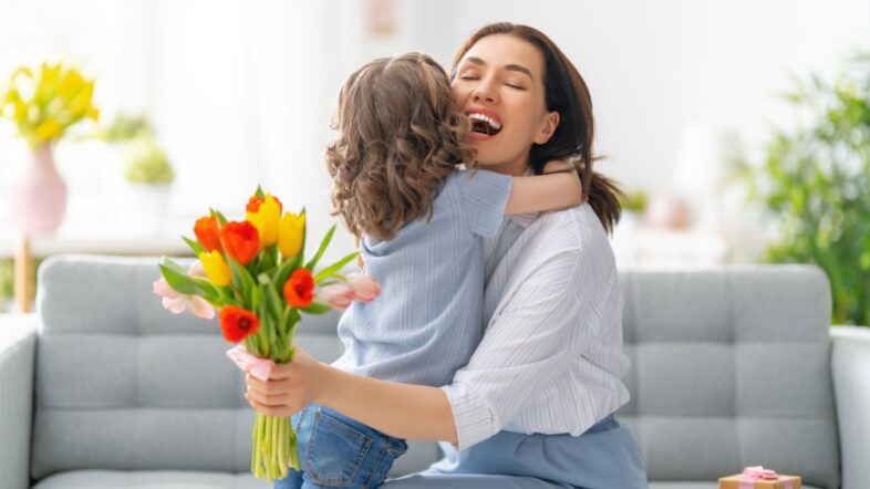 Happy mother's day. Child daughter congratulates mom and gives her flowers.